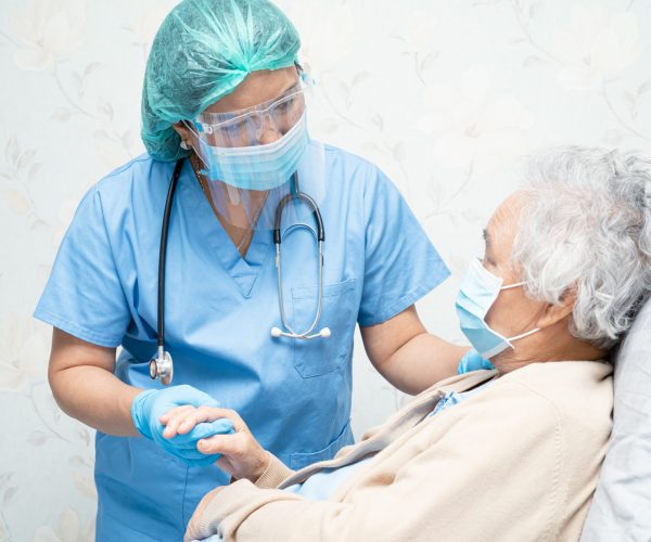 Asian doctor wearing face shield and PPE suit to check patient protect safety infection Covid-19 Coronavirus outbreak at quarantine nursing hospital ward.